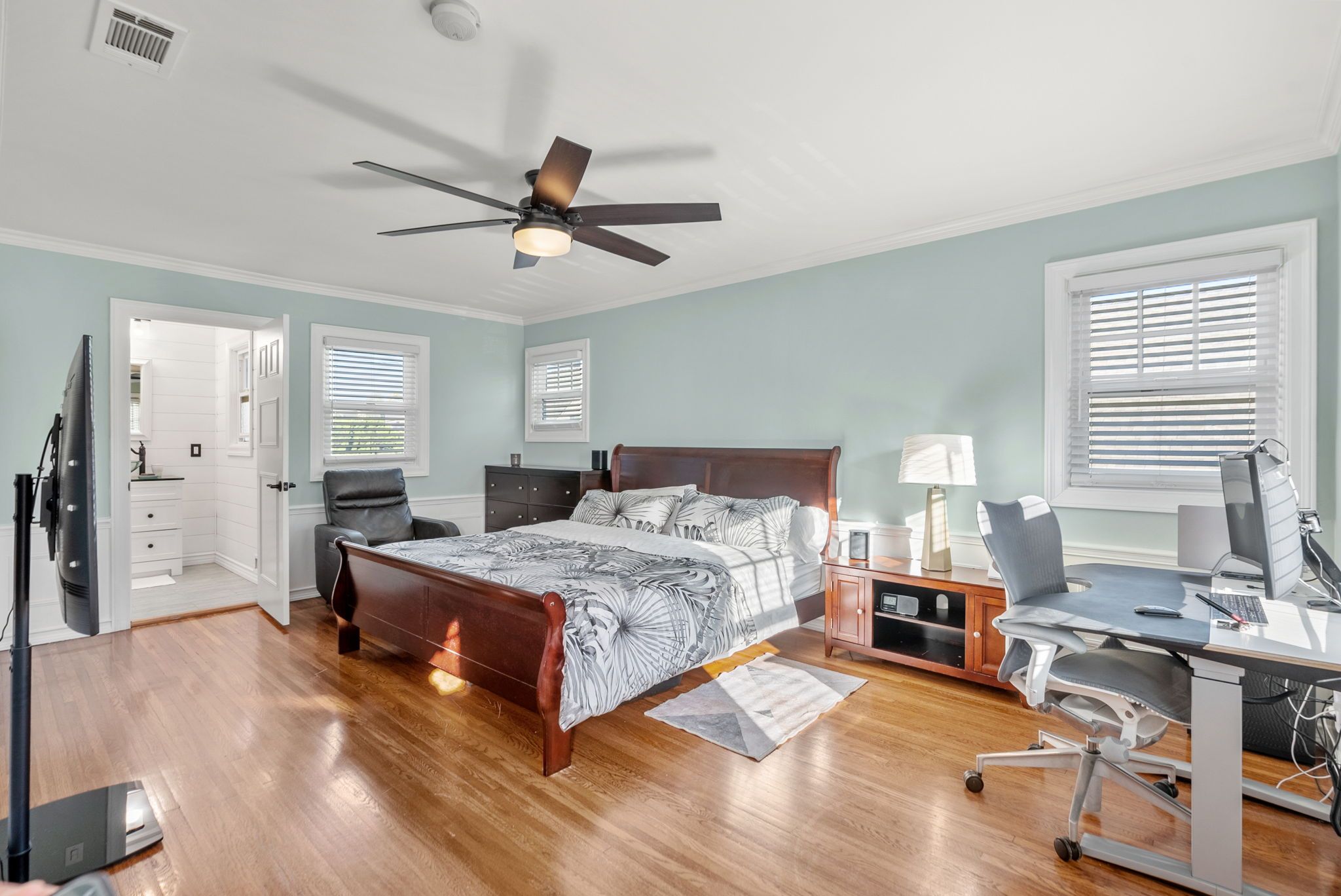 The upstairs bedroom with a king bed, ceiling fan, and a desk by the window